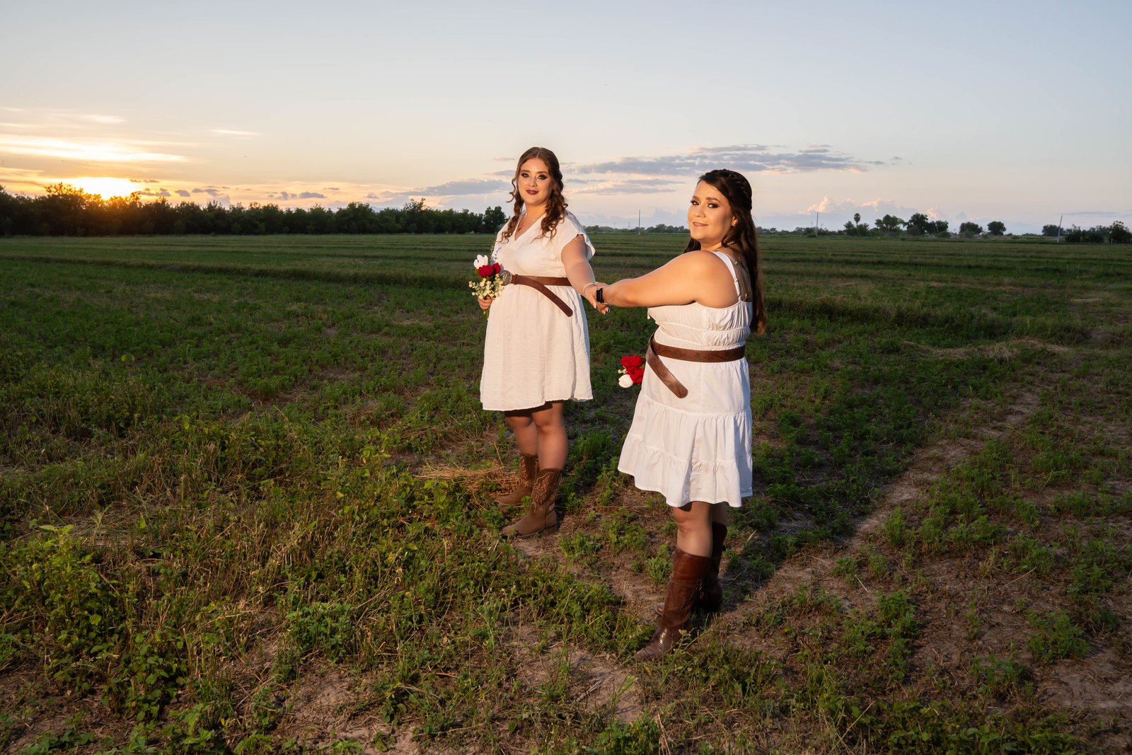 Karina y Yazmín volteando hacia la cámara en el campo, al atardecer